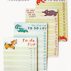 May include: Four colorful to-do list notepads with animal illustrations. The notepads have a yellow, blue, green, and white background with black and red lines. The notepads have the text "to do list" and "like it or not" on them. The notepads have a variety of animals on them, including a cat, a dog, a skunk, and a fox.