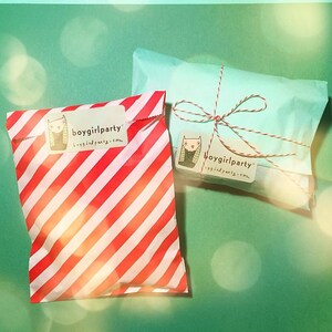 Op de afbeelding: Twee cadeauzakken, een rood-wit gestreept en een lichtblauw, beide met een wit label waarop "boygirlparty boygirlparty.com" staat.