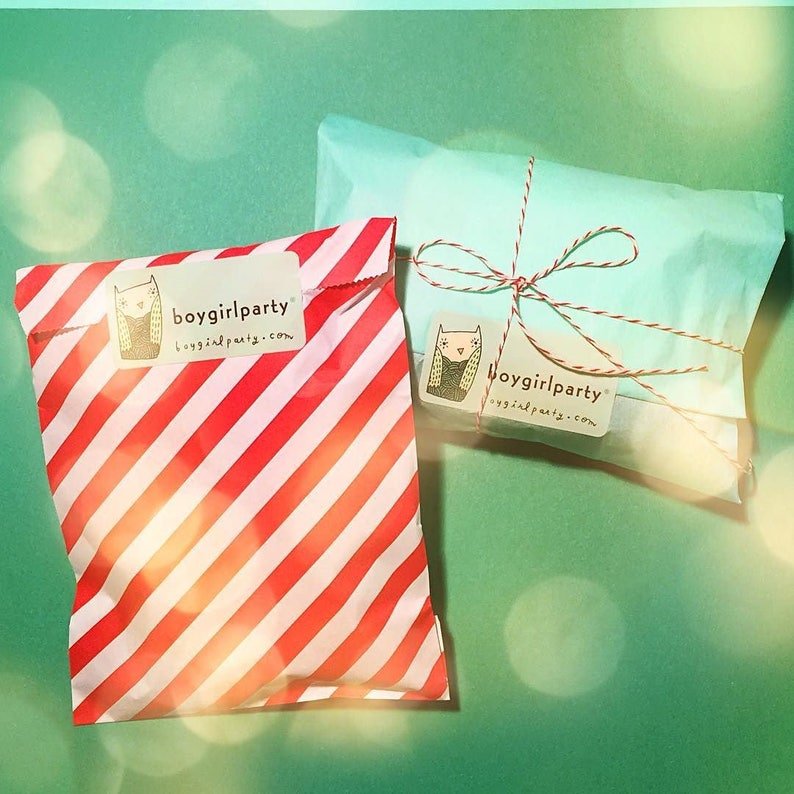 Op de afbeelding: Twee cadeauzakken, een rood-wit gestreept en een lichtblauw, beide met een wit label waarop "boygirlparty boygirlparty.com" staat.
