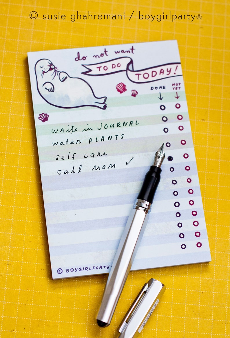 May include: A notepad with the text "do not want to do TODAY!" and a seal illustration. The list includes "write in journal", "water plants", "self care", and "call mom". A silver fountain pen with a black grip and cap is on the notepad.