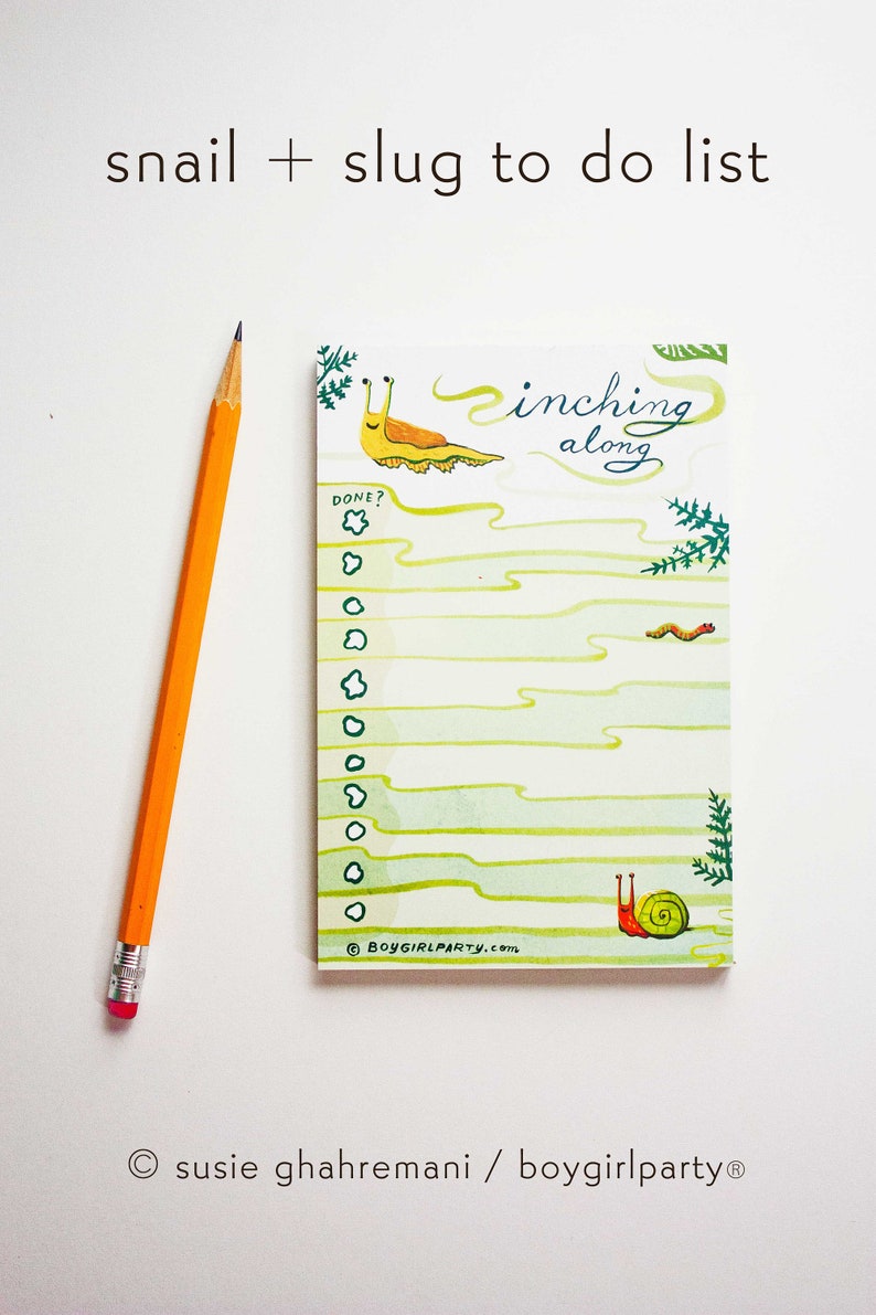 May include: A green and white to-do list notepad with a snail and slug illustration. The notepad has the text "inching along" and "DONE?" with a check box. The notepad is on a white background.