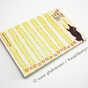 May include: A yellow and white notepad with a black cat illustration and the text "Do not want to do list". The notepad has red circles around the edges and the text "susie ghahremani / boygirlparty" at the bottom.