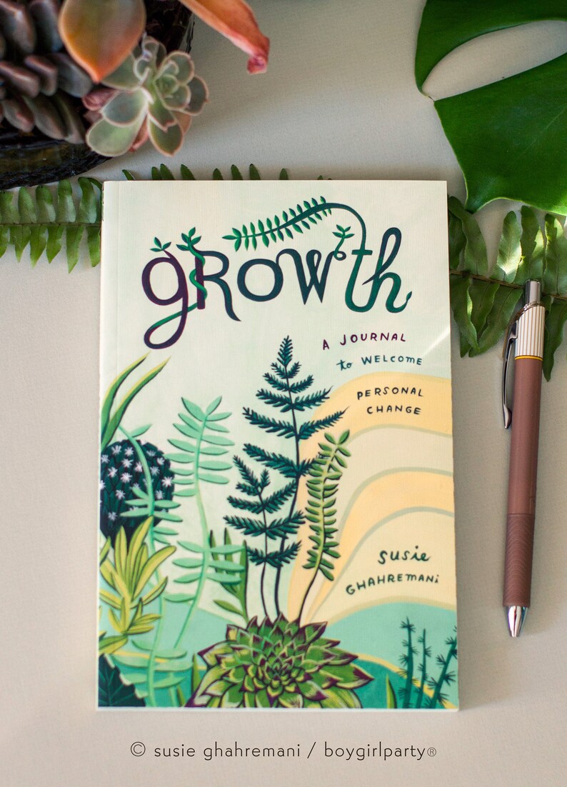 May include: A green, yellow, and white journal with the word "growth" in a stylized font. The journal is decorated with illustrations of plants and ferns. The text "A journal to welcome personal change" is printed on the cover. The author's name, "Susie Ghahremani", is printed at the bottom of the cover.