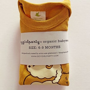 May include: A mustard yellow organic cotton baby onesie with a cute cartoon illustration of a cat. The onesie is folded and has a label that reads "boygirlparty organic babywear" and "SIZE: 6-9 MONTHS".
