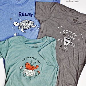 May include: Three t-shirts with different designs. The first t-shirt is blue with a white turtle and the text "RELAX". The second t-shirt is gray with a white coffee cup and the text "COFFEE the LAKE & ME". The third t-shirt is teal with a white turtle and the text "FIND YOUR ADVENTURE".