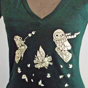 May include: A dark green t-shirt with a white graphic print of three owls around a campfire. The owls are wearing scarves and one is holding a stick with marshmallows on it. The text "boygirlparty&reg;" is printed in white at the top of the shirt.