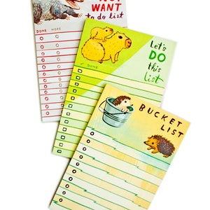 May include: Set of three colorful to-do list notepads featuring illustrations of a possum, capybaras, and hedgehogs. The notepads have the text "Do Not Want to do list", "Let's Do This List", and "Bucket List" on them.