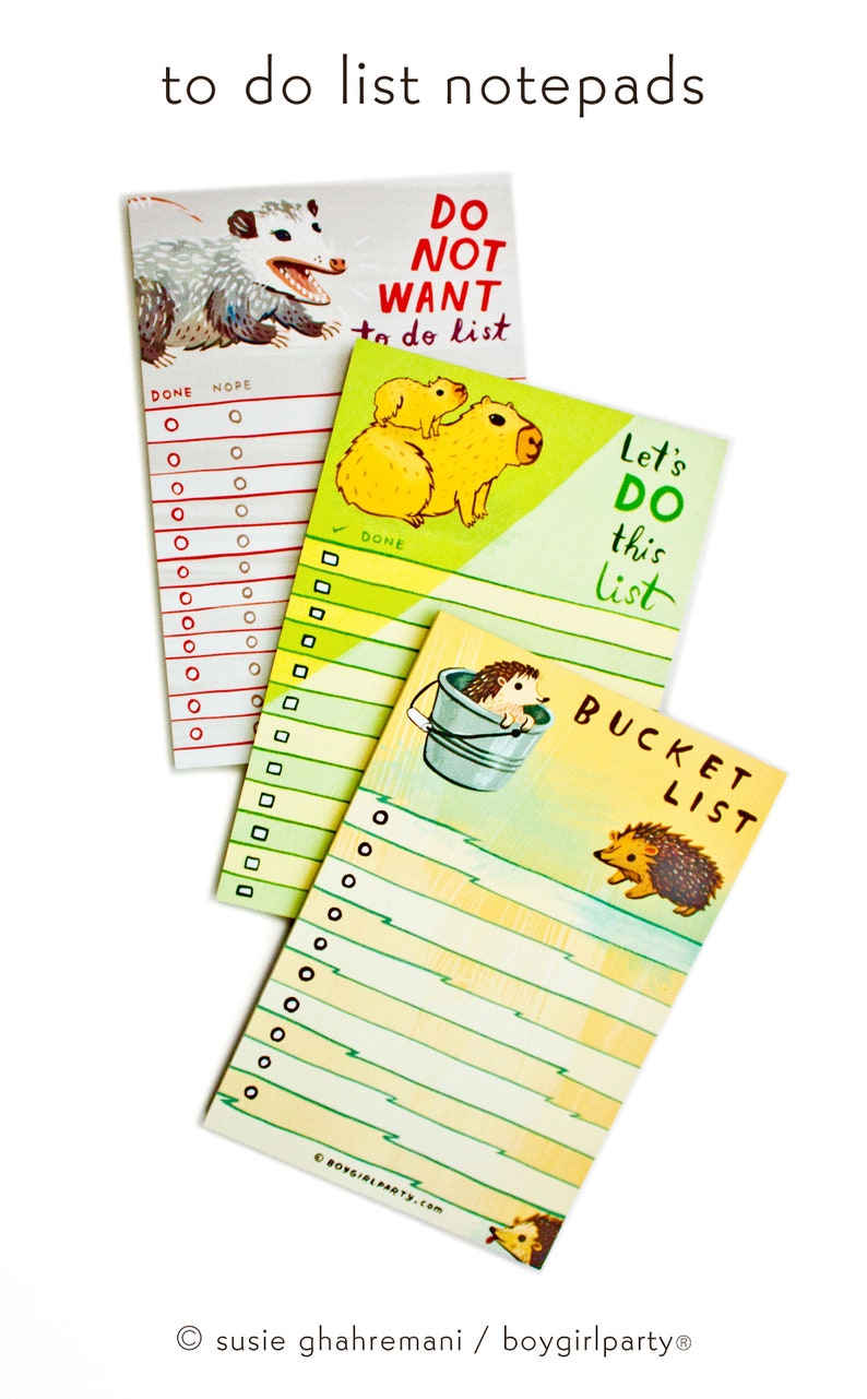May include: Set of three colorful to-do list notepads featuring illustrations of a possum, capybaras, and hedgehogs. The notepads have the text "Do Not Want to do list", "Let's Do This List", and "Bucket List" on them.