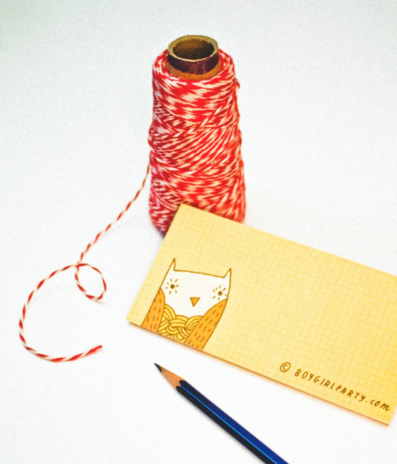 Op de afbeelding: Een gele kaart met een handgetekend ontwerp van een uil met uitgespreide vleugels. De uil houdt een bol wol in zijn klauwen. De kaart heeft de tekst "&copy; boygirlparty.com" in de rechterbenedenhoek.