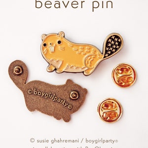 May include: A gold-colored enamel pin featuring a cartoon beaver with a brown tail. The beaver is yellow with a light brown belly and has a small, white tooth showing. The pin is on a white background and has a text overlay that reads "beaver pin".