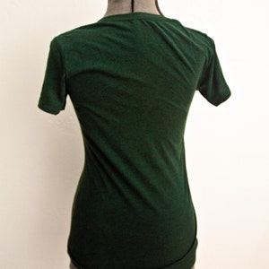 May include: A dark green t-shirt on a mannequin. The t-shirt has short sleeves and a crew neck.