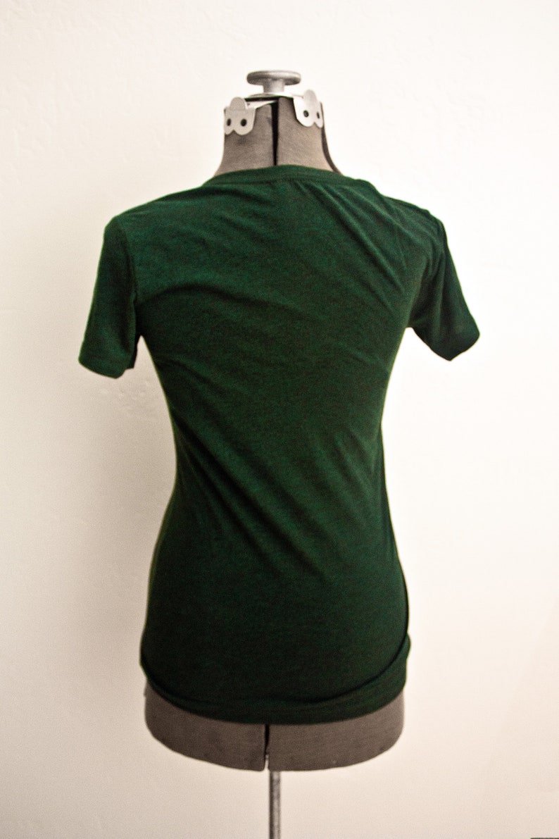 May include: A dark green t-shirt on a mannequin. The t-shirt has short sleeves and a crew neck.