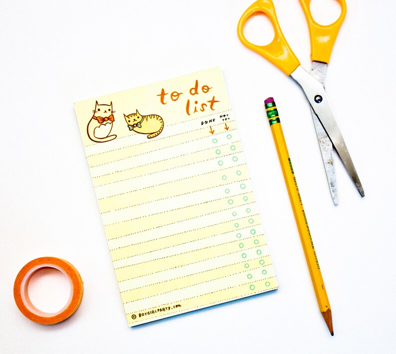May include: A yellow to-do list notepad featuring two cartoon cats wearing bow ties. The notepad has a column of circles for ticking off tasks. The text "to do list" is written in orange at the top of the notepad. A yellow pencil and a pair of silver scissors are also in the image.