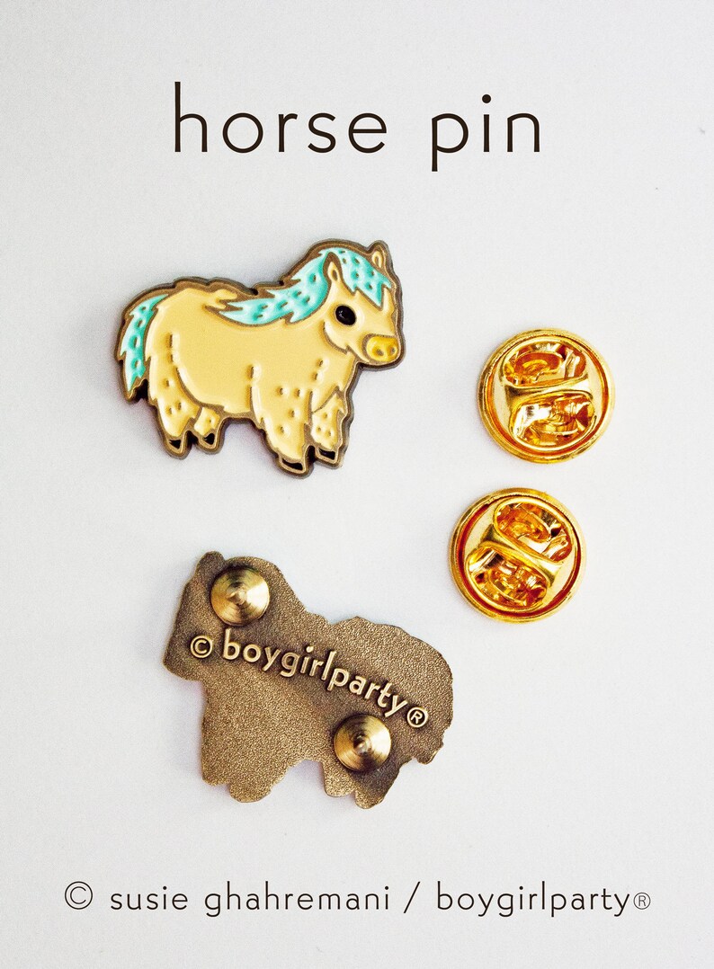 Op de afbeelding: Een gouden emaille pin met een cartoonpaard met een lichtblauwe manen en een geel lichaam. De pin is op een witte achtergrond en bevat de tekst "&copy;boygirlparty&reg;".