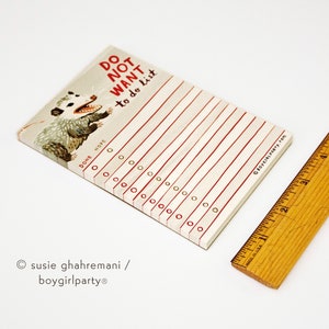May include: A white notepad with red lines and a black and white illustration of a possum. The notepad has the text "DO NOT WANT to do list" written in red. The notepad has a section for "DONE" and "NOPE" with checkboxes.