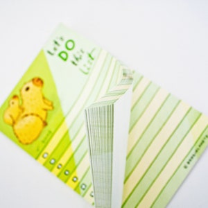 May include: A green and yellow notepad with a cartoon illustration of a mother and baby capybara. The notepad has the text "Let's Do This List" on the front.