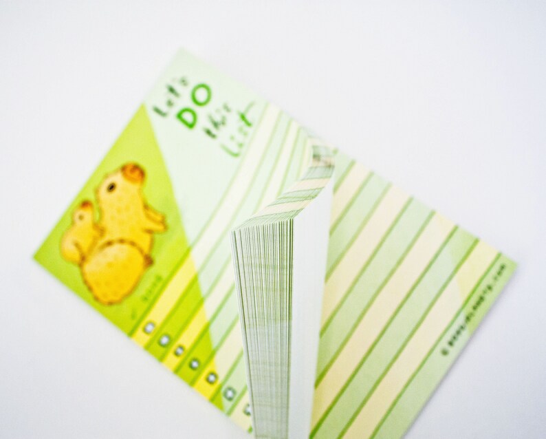 May include: A green and yellow notepad with a cartoon illustration of a mother and baby capybara. The notepad has the text "Let's Do This List" on the front.