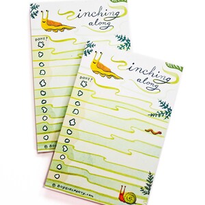May include: Two yellow and green to-do list notepads with a snail and slug illustration. The notepads have the text "inching along" and "DONE?" printed on them.