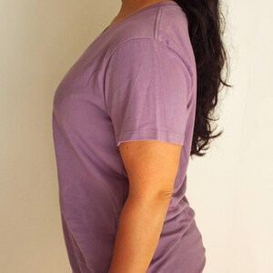 May include: A plain, light purple t-shirt with a v-neck and short sleeves.