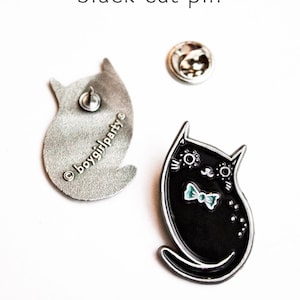 May include: Black enamel cat pin with a blue bow tie. The back of the pin is silver and says "&copy;boygirlparty."