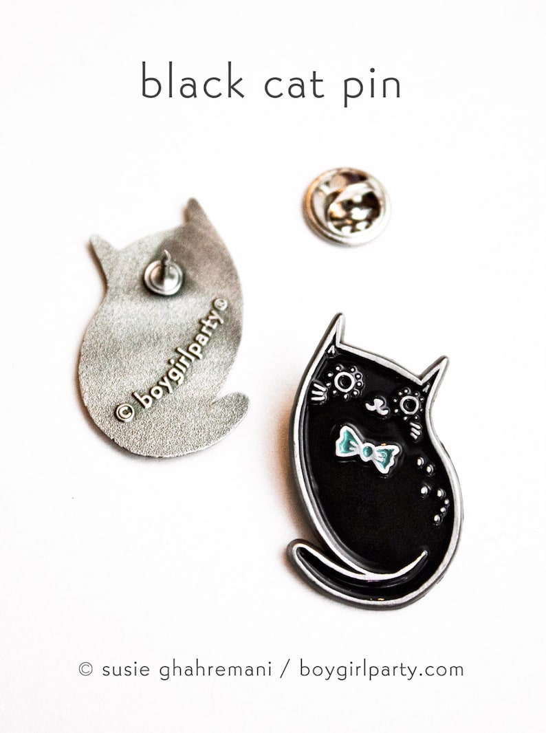 May include: Black enamel cat pin with a blue bow tie. The back of the pin is silver and says "&copy;boygirlparty."