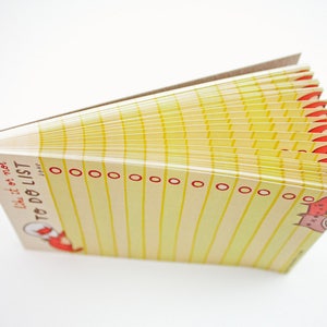 May include: A yellow and white to-do list notepad with red and white illustrations of a cat. The notepad has the text "like it or not TO DO LIST JONE" printed on the front.