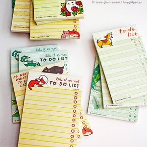 May include: A set of colorful notepad sets with illustrations of animals and the text "like it or not to do list" on a yellow background. The notepads are stacked on top of each other and have a white background.