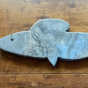 Puede incluir: Una decoración de pared de madera en forma de pez gris y azul con un acabado marmoleado.