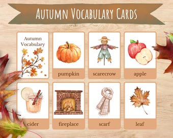 May include: Autumn vocabulary cards with illustrations of a pumpkin, scarecrow, apple, cider, fireplace, scarf, and leaf. The cards are on a wood background.