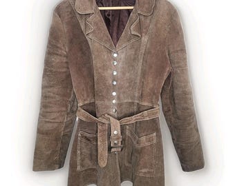 May include: Brown suede jacket with a notched collar, button closure, and a matching belt. The jacket features two front pockets and is hanging on a wooden hanger. The jacket is a medium length.