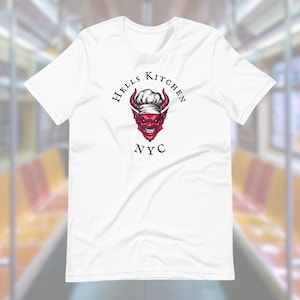 May include: White t-shirt with a red devil chef graphic and the text "Hells Kitchen NYC". The devil is wearing a chef's hat and has horns. The design is centered on the front of the shirt.