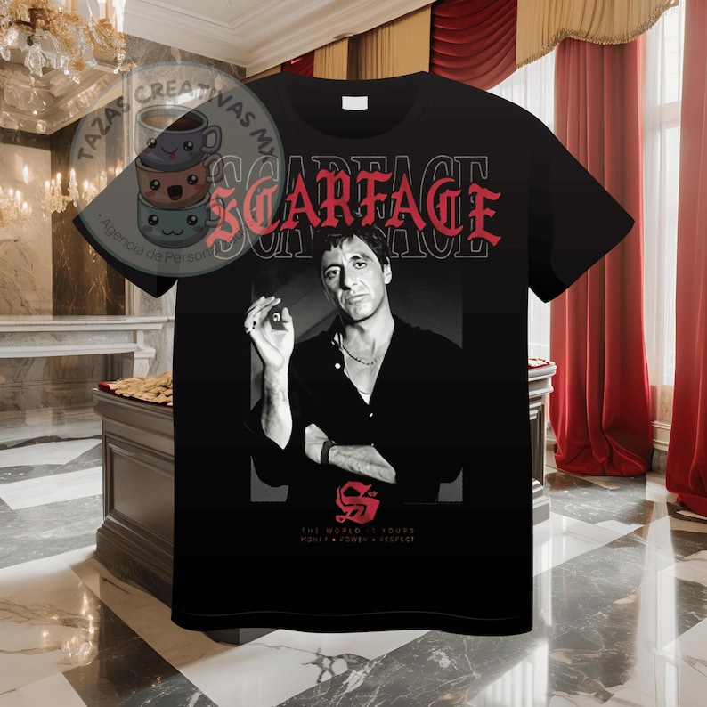 Pode incluir: Camiseta preta com um gr&aacute;fico branco e vermelho de Al Pacino como Tony Montana do filme Scarface. O texto "Scarface" est&aacute; em vermelho e o texto "The World is Yours" est&aacute; em branco.