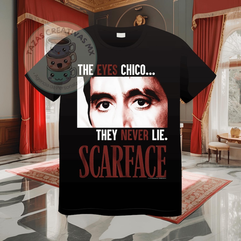 Pode incluir: Camiseta preta com um gr&aacute;fico vermelho dos olhos de Al Pacino do filme Scarface. O texto "THE EYES CHICO... THEY NEVER LIE. SCARFACE" est&aacute; impresso na camiseta.