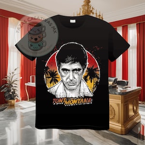 Pode incluir: Camiseta preta com um gr&aacute;fico de Tony Montana do filme Scarface. O gr&aacute;fico apresenta um p&ocirc;r do sol, palmeiras e o texto "Tony Montana".