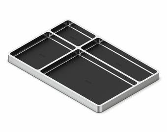 Puede incluir: Una bandeja organizadora rectangular con marco plateado e interiores negros. La bandeja está dividida en cinco secciones de diferentes tamaños, ideal para organizar objetos pequeños. El diseño es moderno y minimalista.