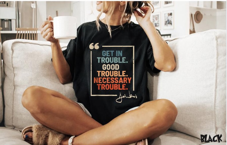 May include: Black t-shirt with a quote by John Lewis in a vintage style font. The quote reads "Get in trouble. Good trouble. Necessary trouble."