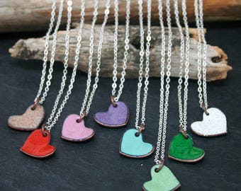 May include: A collection of silver chain necklaces with small heart-shaped pendants. The pendants are made of ceramic and are painted in various colours, including red, pink, purple, turquoise, green, and white.