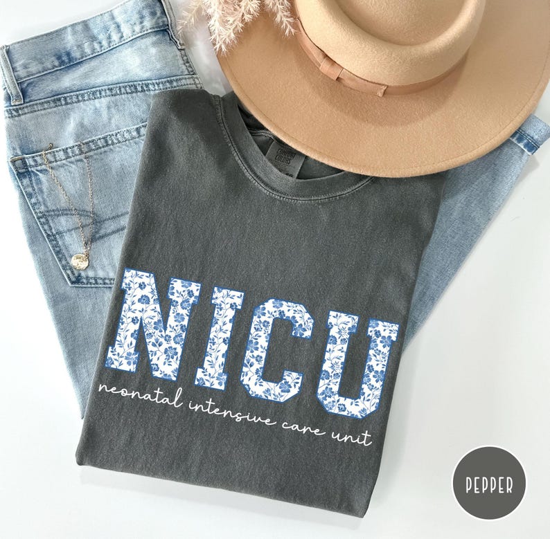 May include: A gray t-shirt with a white floral design that spells out "NICU" and the text "neonatal intensive care unit".