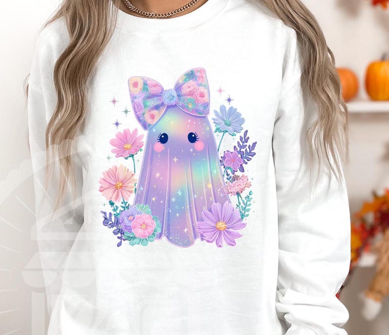 Pode incluir: Camisola branca com um personagem de fantasma fofo com um la&ccedil;o floral e rodeado por flores pastel. O fantasma tem um design colorido e iridescente. Perfeito para o Halloween ou uma est&eacute;tica caprichosa.