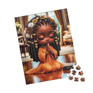 May include: A jigsaw puzzle depicting a dark-skinned child with braided hair adorned with gold and white flowers, wearing an orange dress, kneeling with hands in prayer next to a book labeled BIBLE, with several loose puzzle pieces at the bottom.