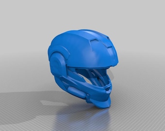 May include: A solid blue helmet with a futuristic design. The helmet features a visor area, ear pieces, and a top section with angular details. The overall shape suggests a protective head covering, possibly for sports or cosplay.