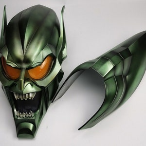 Op de afbeelding: Groen en oranje plastic Green Goblin-masker met een grote, tandenrijke grijns. Het masker bestaat uit twee delen, met een apart deel voor de bovenkant van het hoofd.