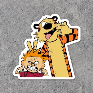 May include: A sticker featuring a cartoon tiger and a boy. The tiger is orange and black with a white stripe down its back. The boy is wearing a red shirt and has red hair. The tiger is sticking its tongue out and the boy is making a funny face.
