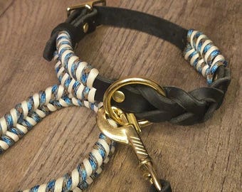 Set composto da collare e guinzaglio in pelle nera per cani, con dettagli in paracord intrecciato color crema e blu.
