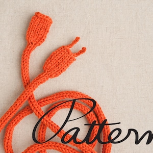 Op de afbeelding: Een feloranje gebreid koord met twee lussen aan de uiteinden. Het koord is opgerold en het woord "Pattern" is in zwarte cursieve letters op de stof geschreven.