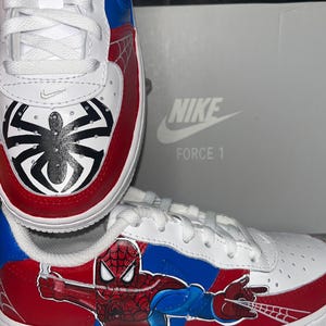 May include: A white ceramic mug with a black handle and the text "But First, Coffee" in a bold, black font. The mug is set against a blurred background, suggesting a cozy setting.