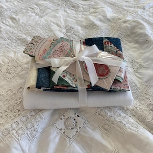 May include: A set of three ceramic mugs with a speckled, cream-colored glaze. Each mug features a different hand-painted design: a blue and green leaf, a yellow flower, and a red berry. The mugs have a simple, rounded shape and a comfortable handle.