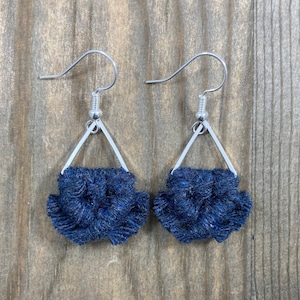 May include: A pair of dark blue fabric earrings with a silver triangle frame and silver hooks.
