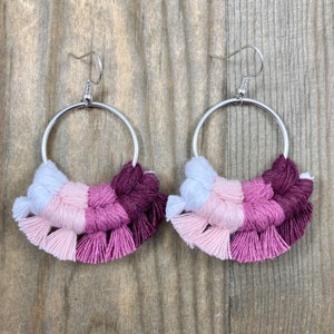 May include: A pair of silver hoop earrings with pink, white, and burgundy tassel fringe.