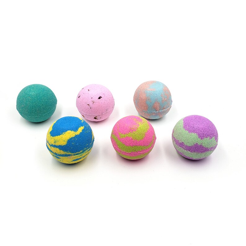 May include: Six colorful bath bombs in various shades of blue, green, pink, and purple. The bath bombs are round and have a marbled appearance.